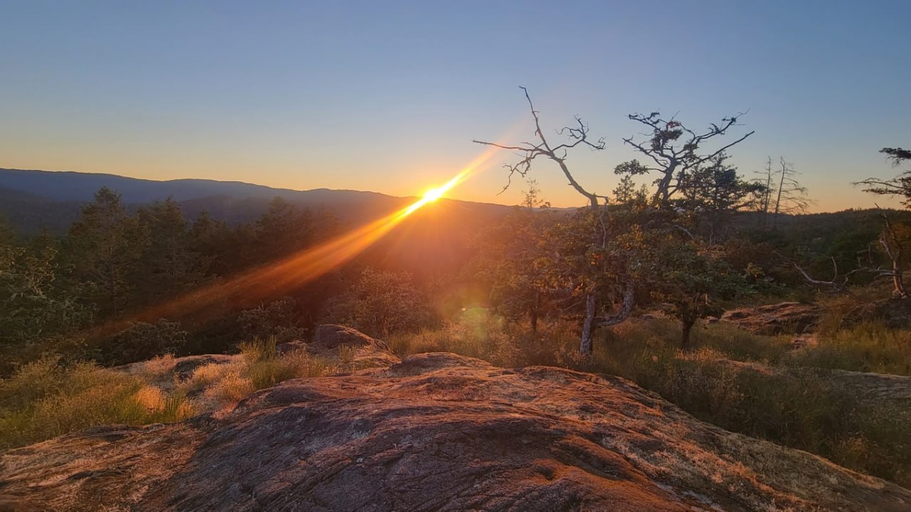 Golden-hour light on rocky outcrops above island hills